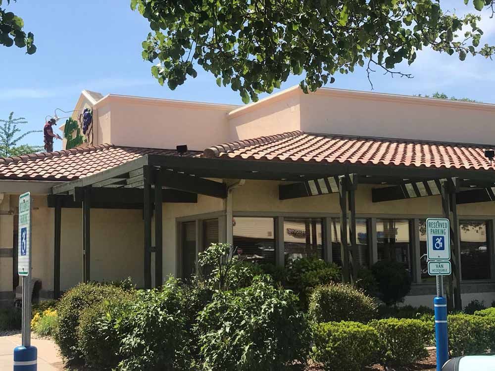Exterior view of a restaurant with a tiled roof and accessible parking sign in front.