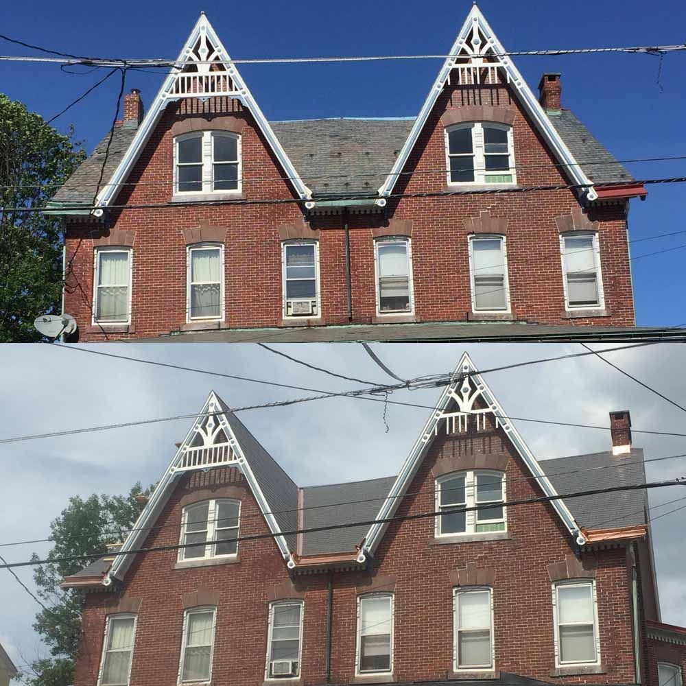 Two-story brick house with two pointed gables, white trim, and multiple windows. Overhead power lines.