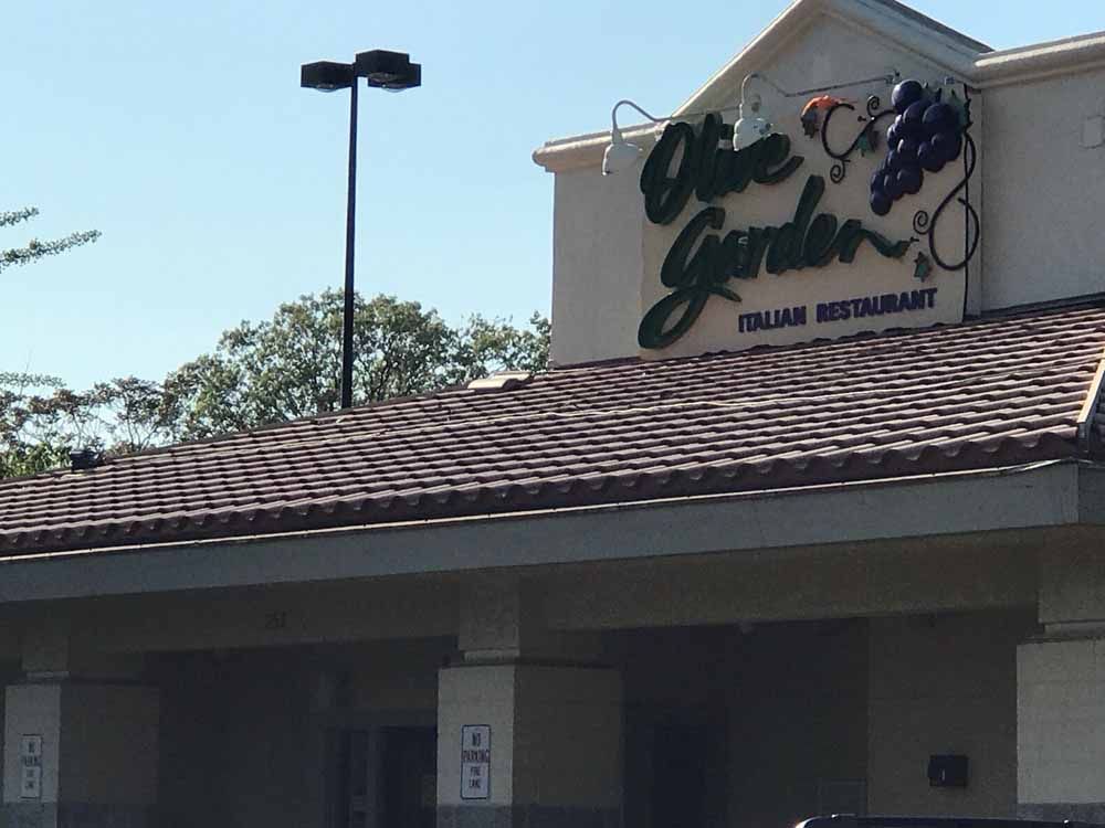 Olive Garden Italian Restaurant exterior with sign, brown roof, and blue sky.