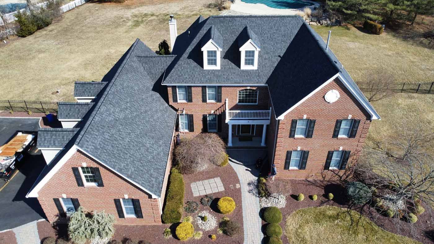 Large brick house with a dark gray roof and landscaping.