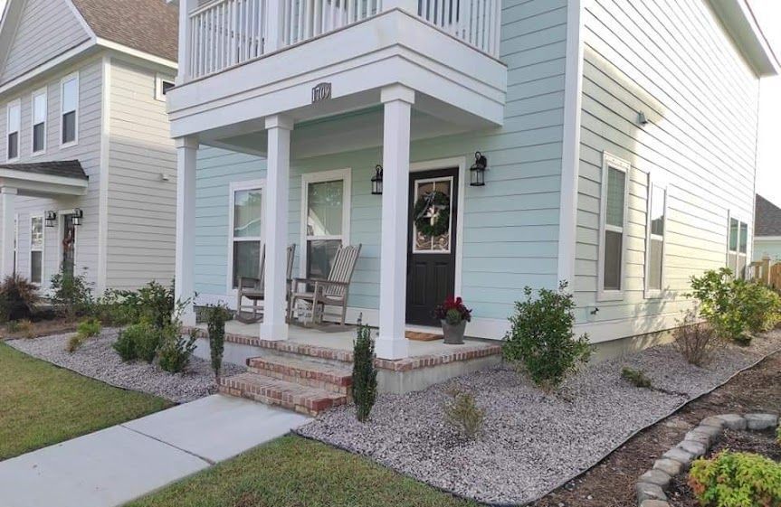 A house with a porch and rocking chairs on it.