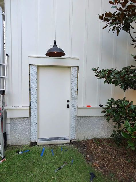 A white door is sitting on the side of a house next to a tree.