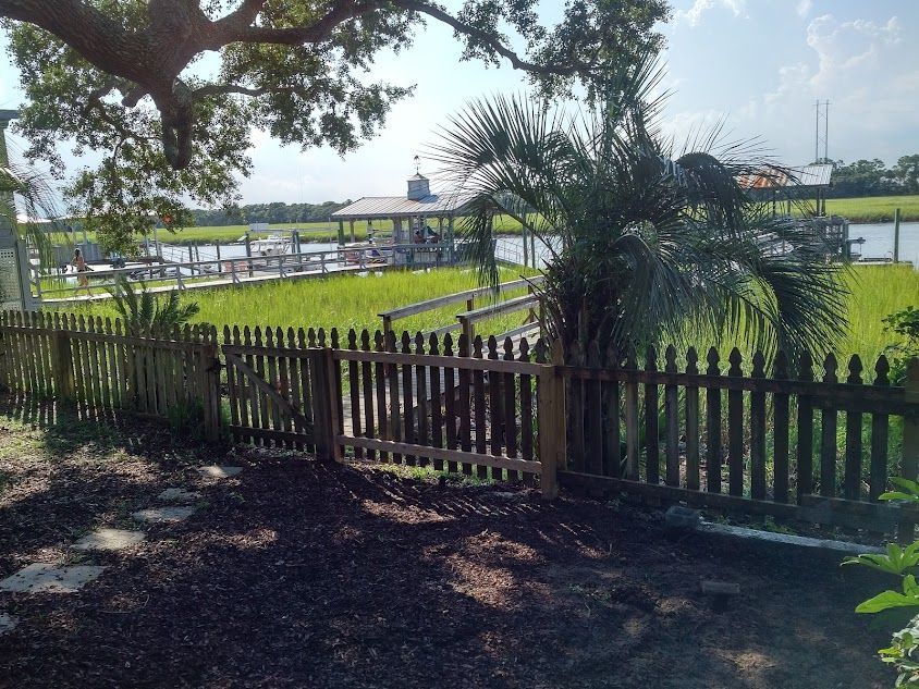 A wooden picket fence with a boat in the background