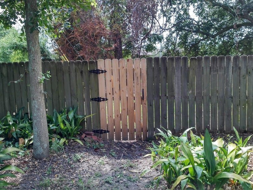 A wooden fence with a wooden gate in the middle of it.