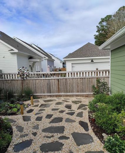 A stone walkway leading to a house with a wooden fence.