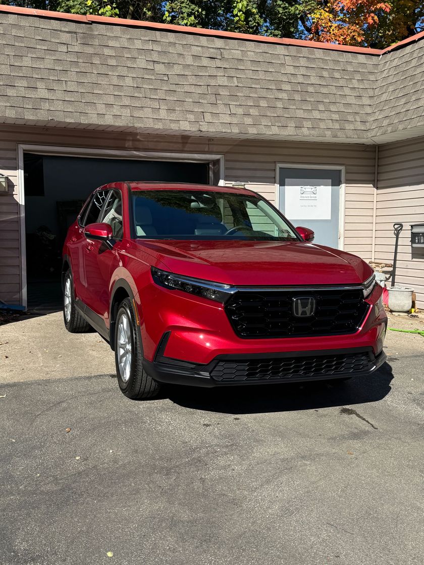 A red Honda CR-V SUV parked on a driveway in front of a garage.