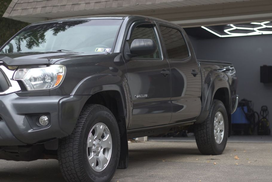 A gray Toyota Tacoma pickup truck parked in a driveway in front of a garage.