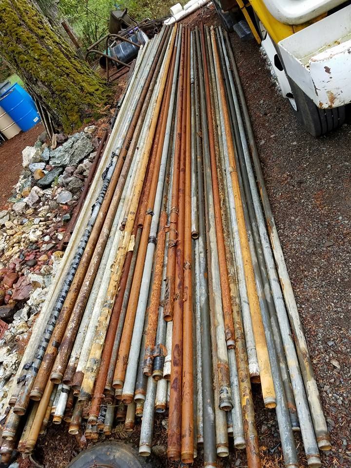 Pile of weathered metal poles on the ground, likely construction or utility related, with varying rust colors. Pile of weathered metal poles on the ground, likely construction or utility related, with varying rust colors.