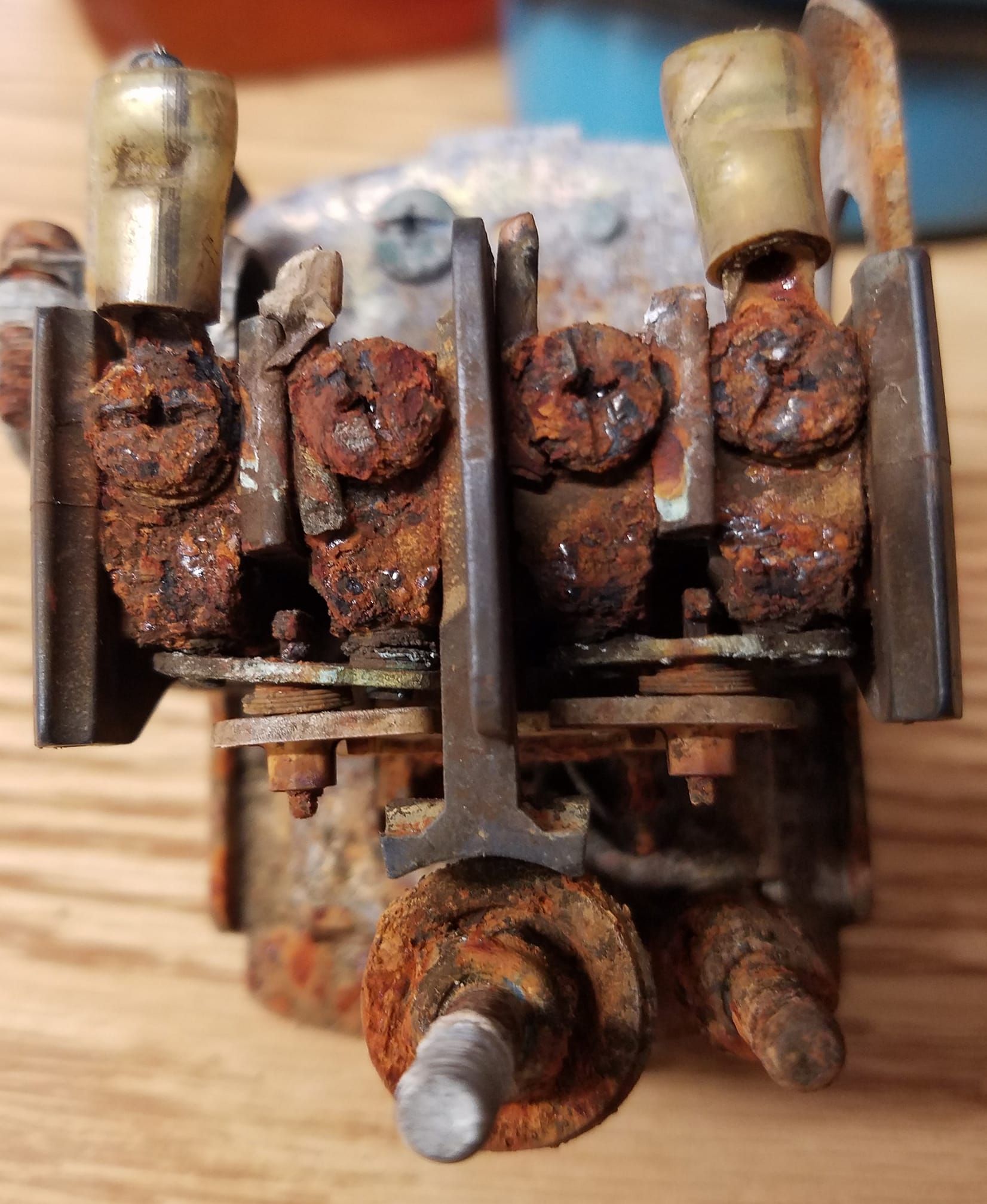 Heavily corroded electrical component with brass connectors, rusted screws, and metal parts.