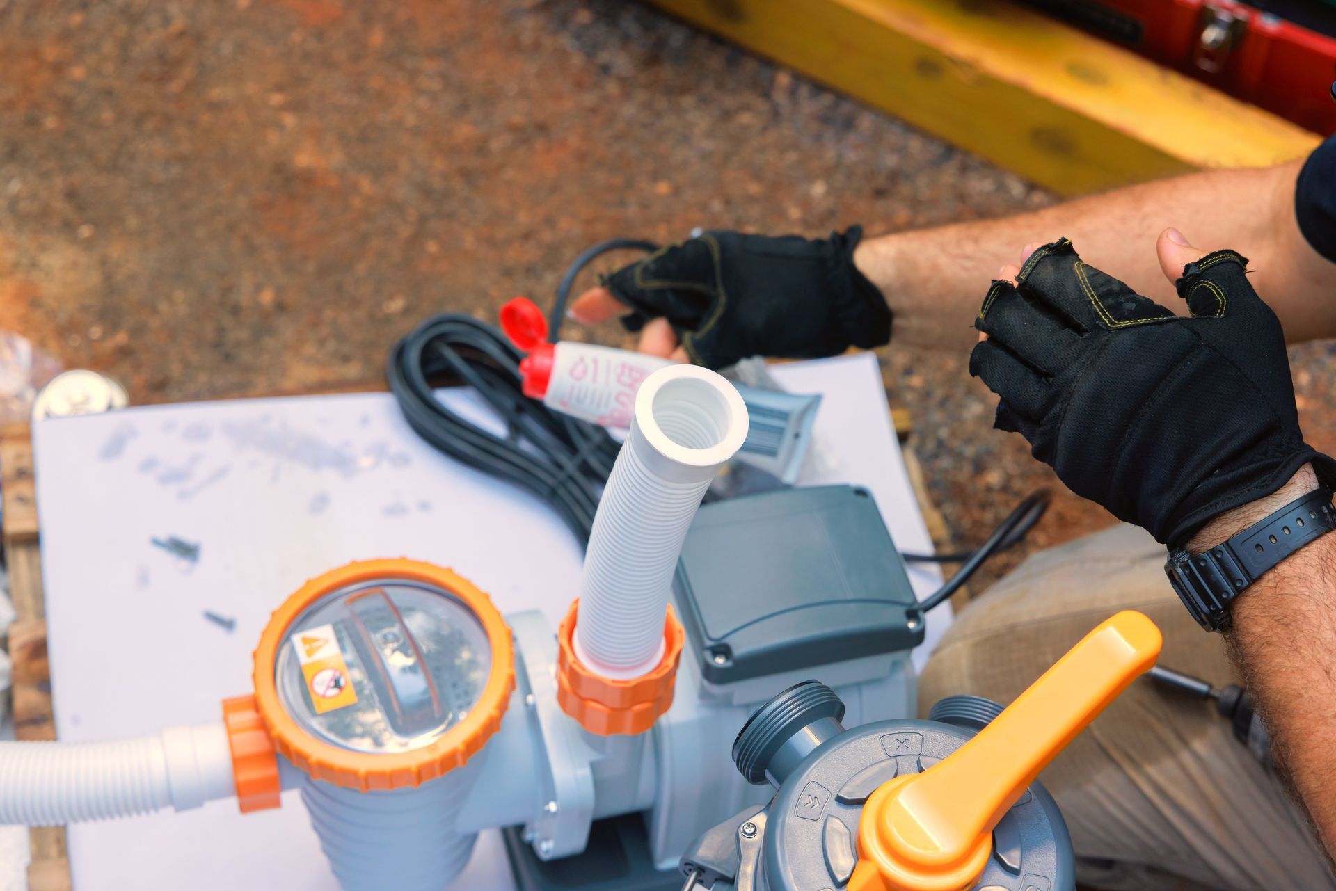 Hands in black gloves assembling pool pump with orange and white pipes. Hands in black gloves assembling pool pump with orange and white pipes.