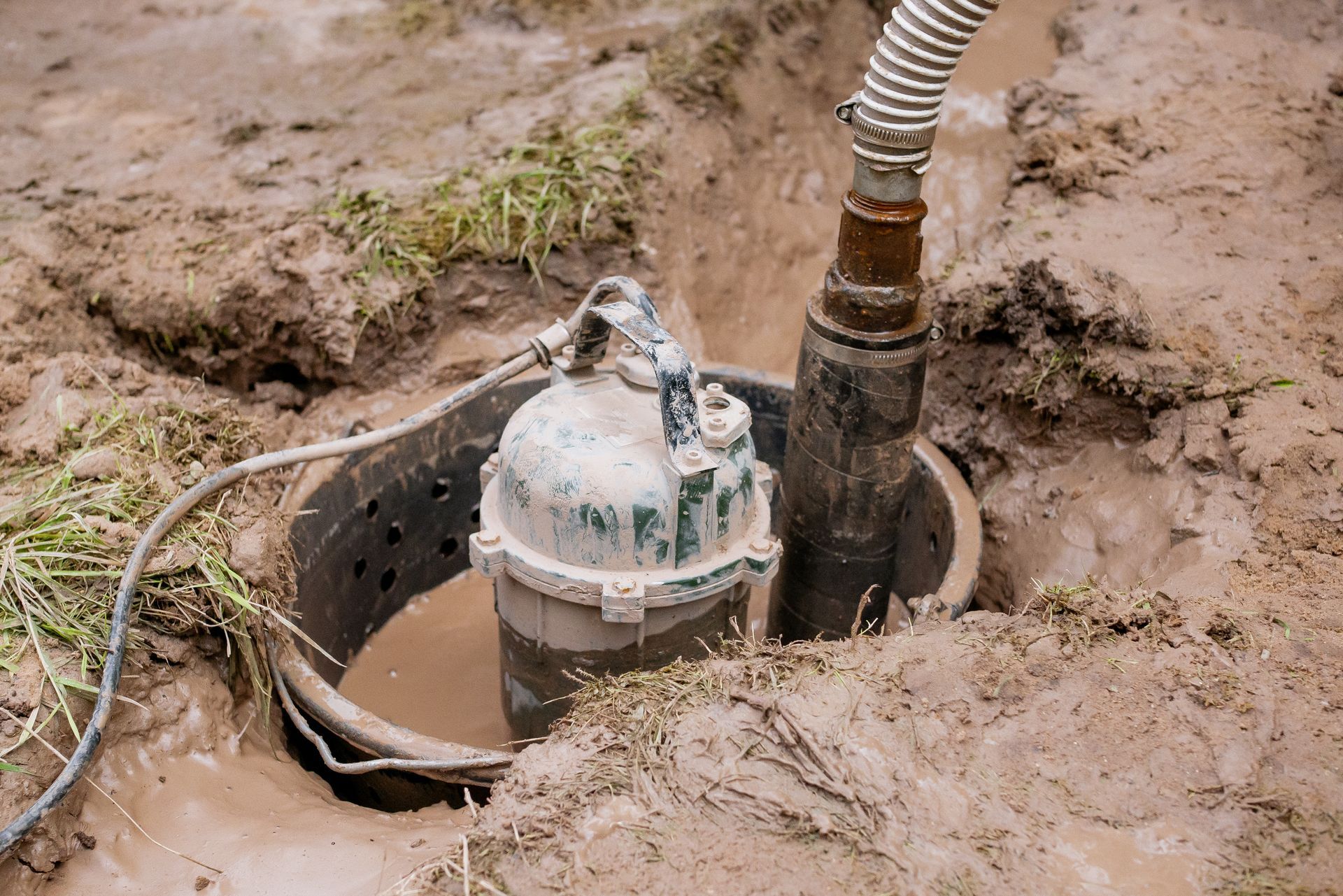 Submersible pump in a muddy pit, pumping water through a hose. Submersible pump in a muddy pit, pumping water through a hose.