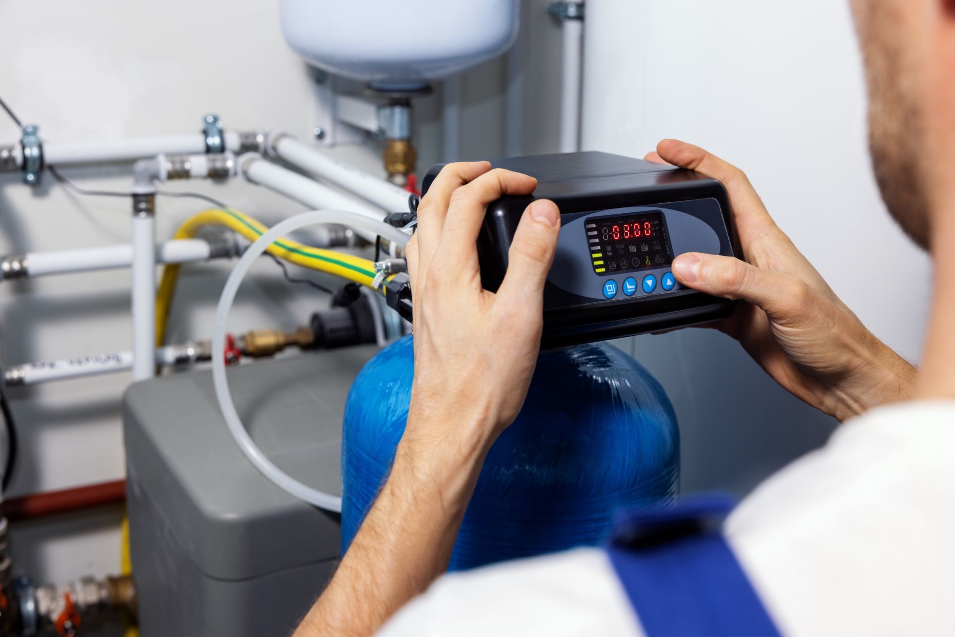 Person adjusting a control panel on a water softener system. Person adjusting a control panel on a water softener system.