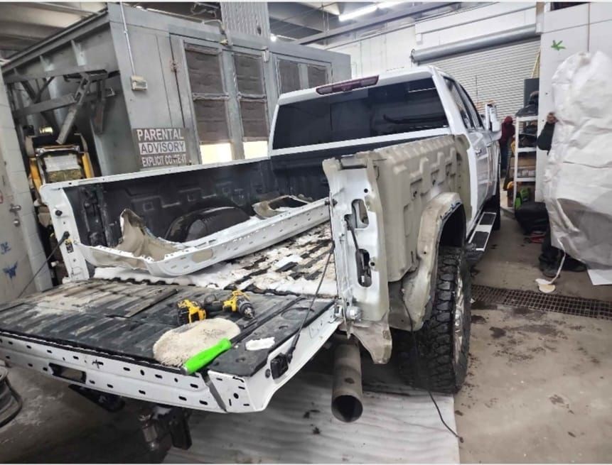 A white truck is being repaired in a garage.