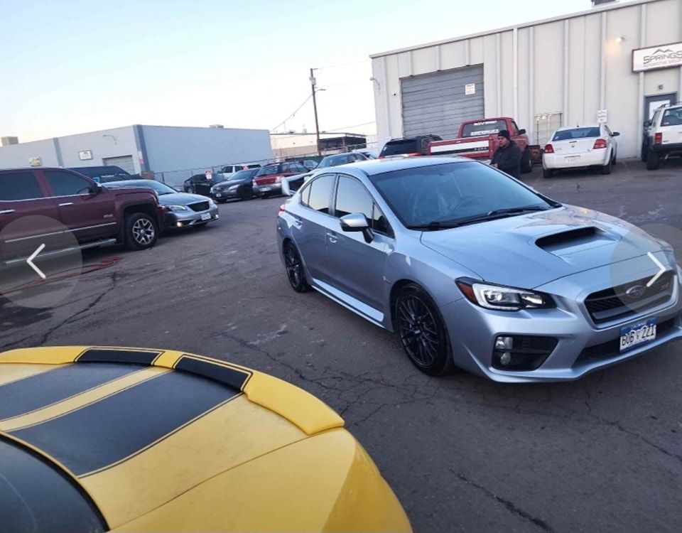 A silver car is parked next to a yellow car