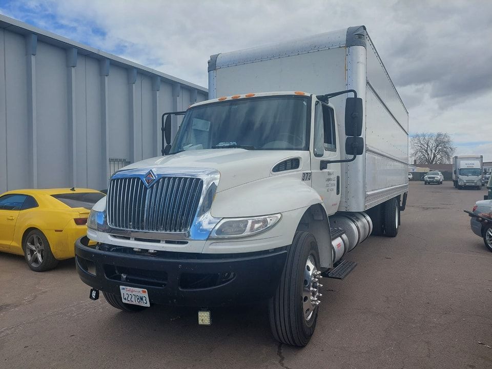 A white semi truck is parked in a parking lot next to a yellow car.