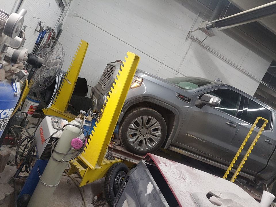 A gray truck is sitting on a yellow lift in a garage.