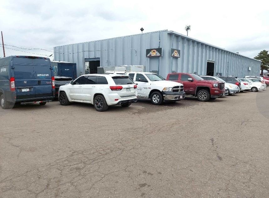 A row of cars are parked in front of a building.