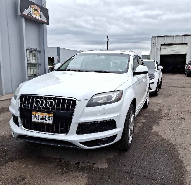 A white audi is parked in front of a building