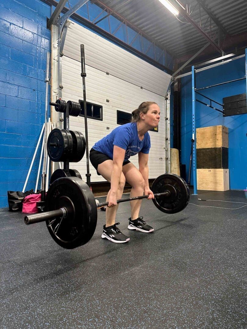 A woman is lifting a barbell in a gym.