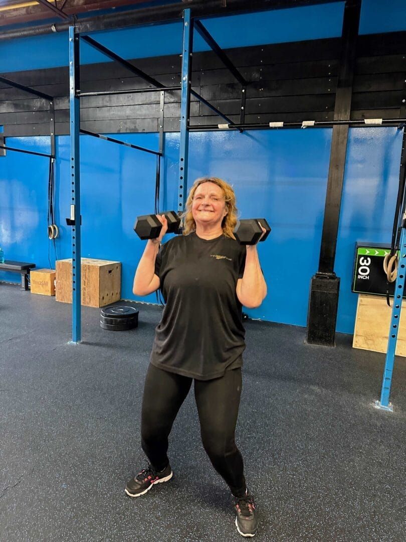 A woman is lifting dumbbells in a gym.