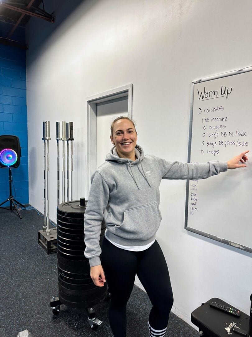 A woman is pointing at a whiteboard in a gym.