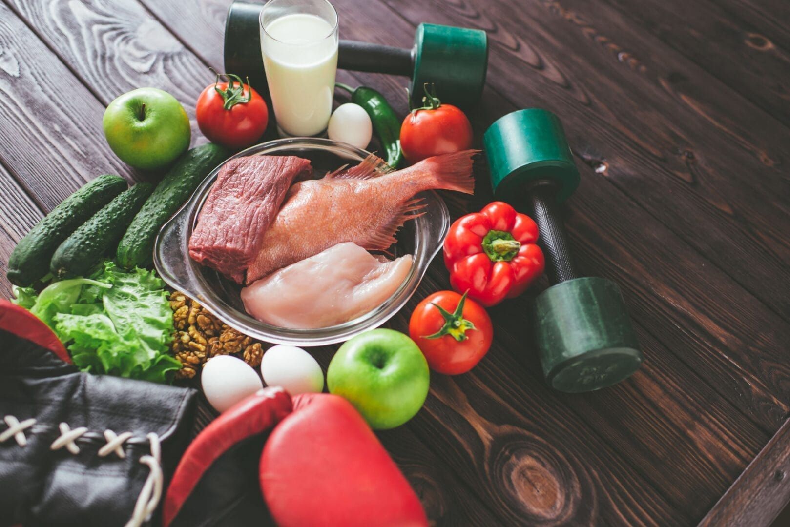 A wooden table topped with a variety of healthy foods and boxing gloves.