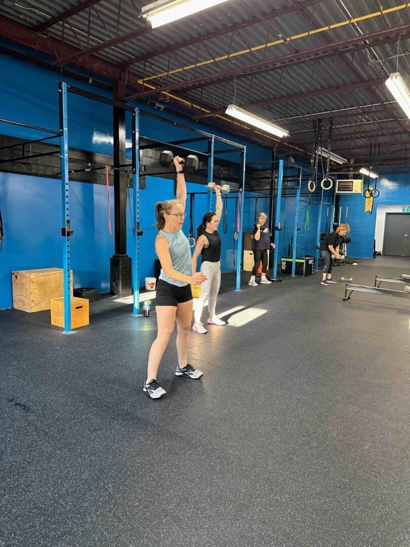 A woman is lifting a kettlebell in a gym.