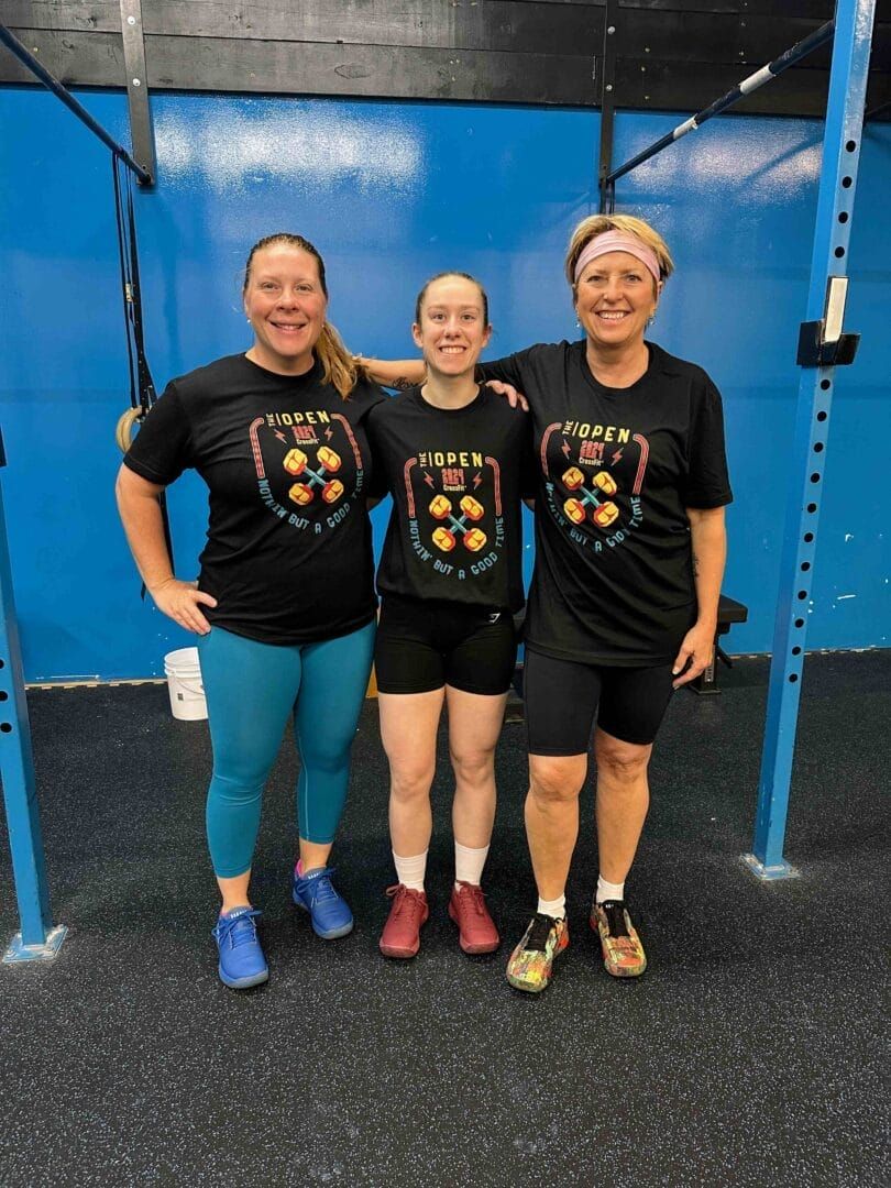 Three women are posing for a picture in a gym.