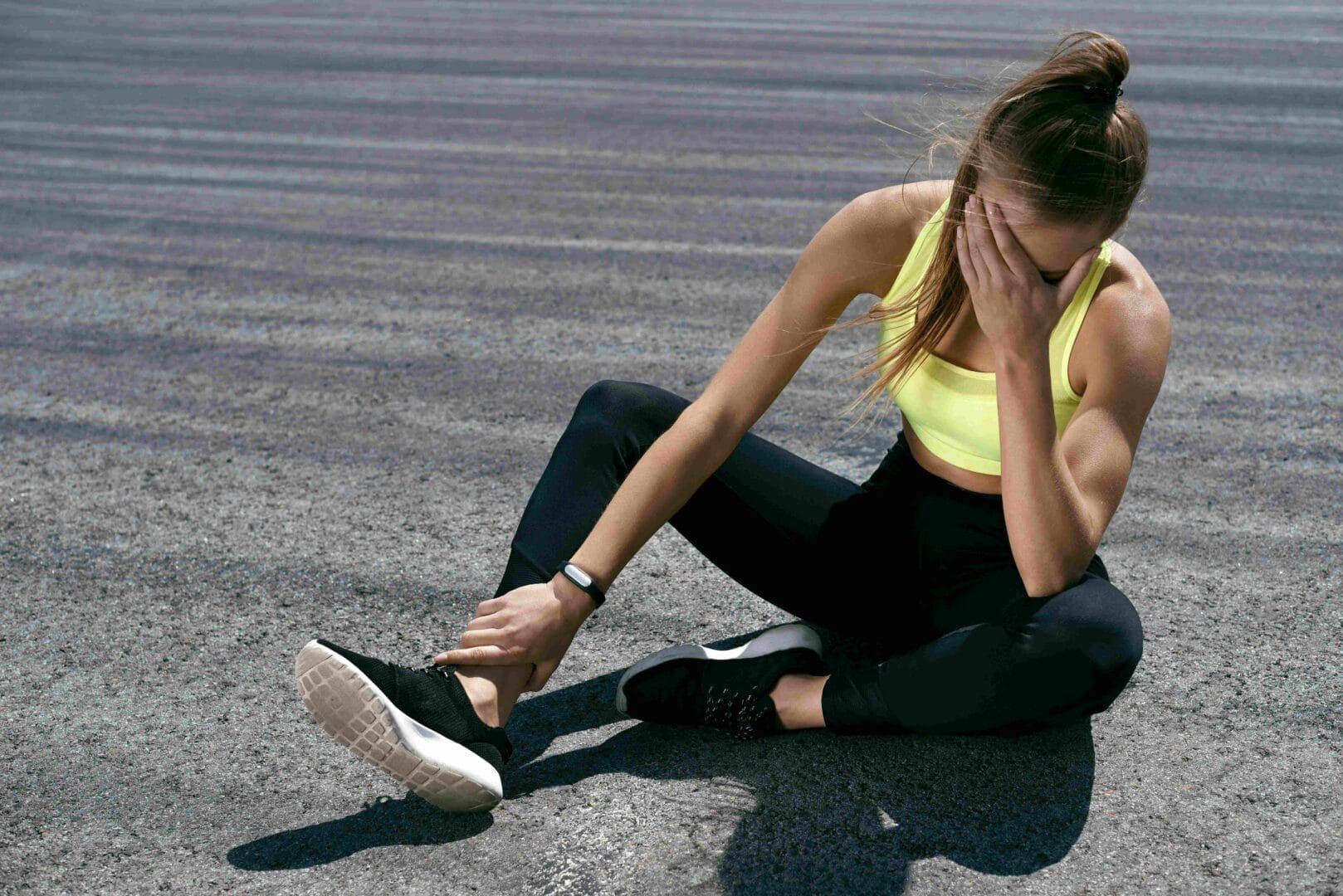 A woman is sitting on the ground with her head in her hands.