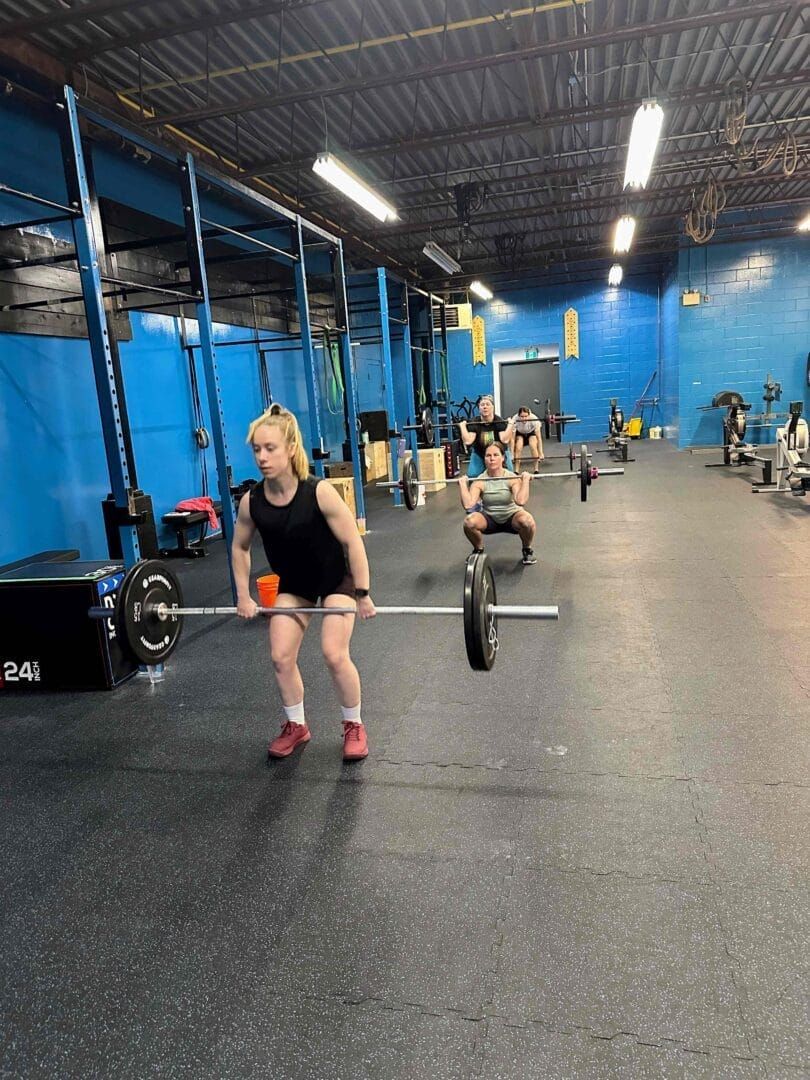 A woman is lifting a barbell in a gym.