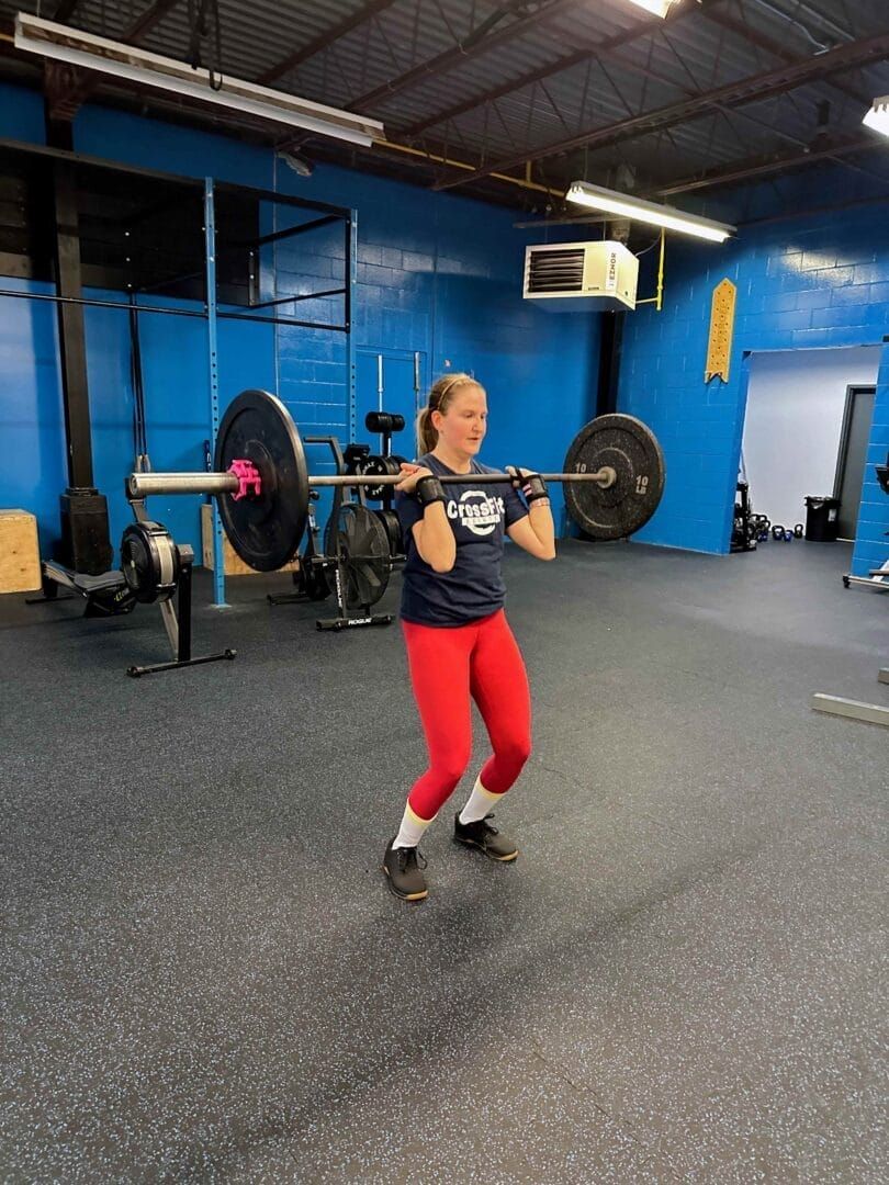 A woman is squatting with a barbell in a gym.