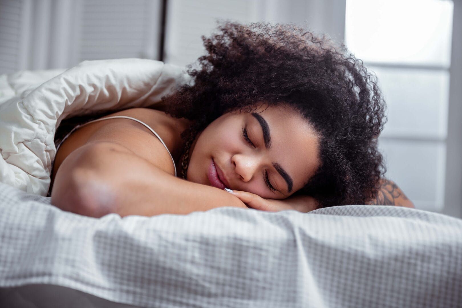 A woman is sleeping in a bed with her eyes closed.