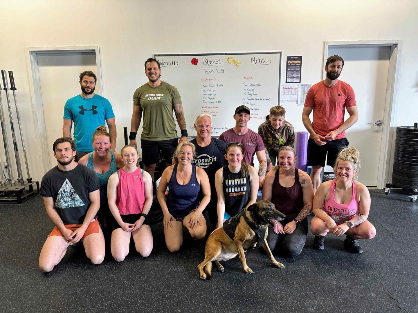 A group of people and a dog are posing for a picture in a gym.