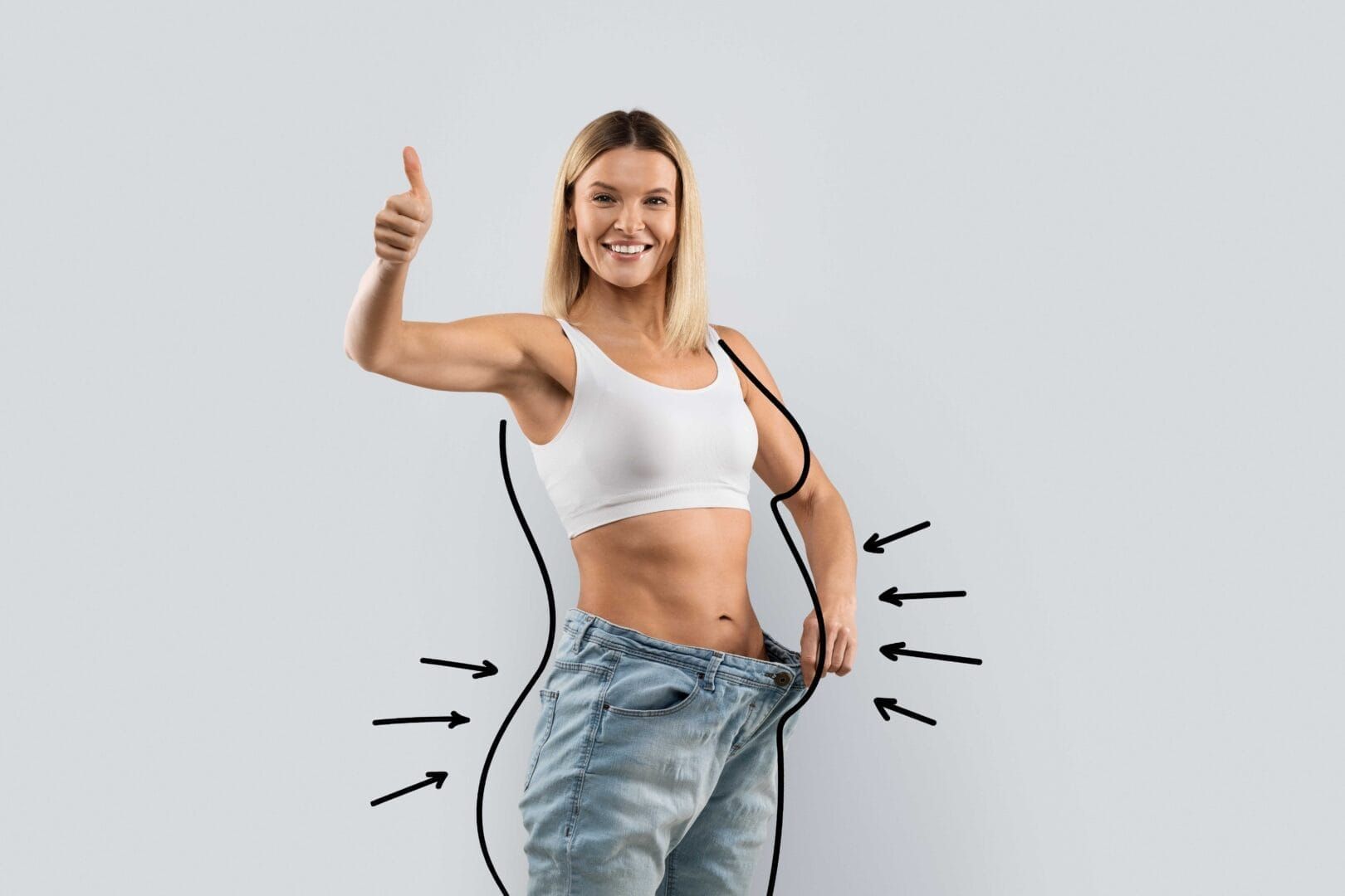 A woman in a white tank top and jeans is giving a thumbs up.