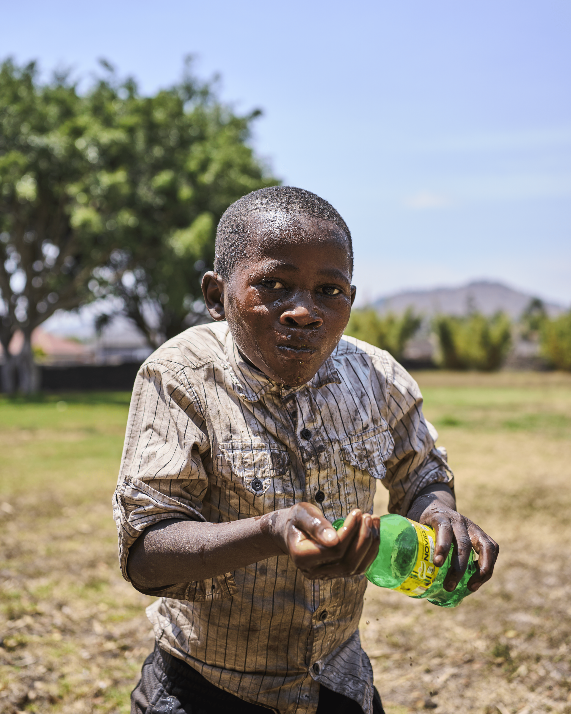 A young boy is holding a green bottle in his hands.