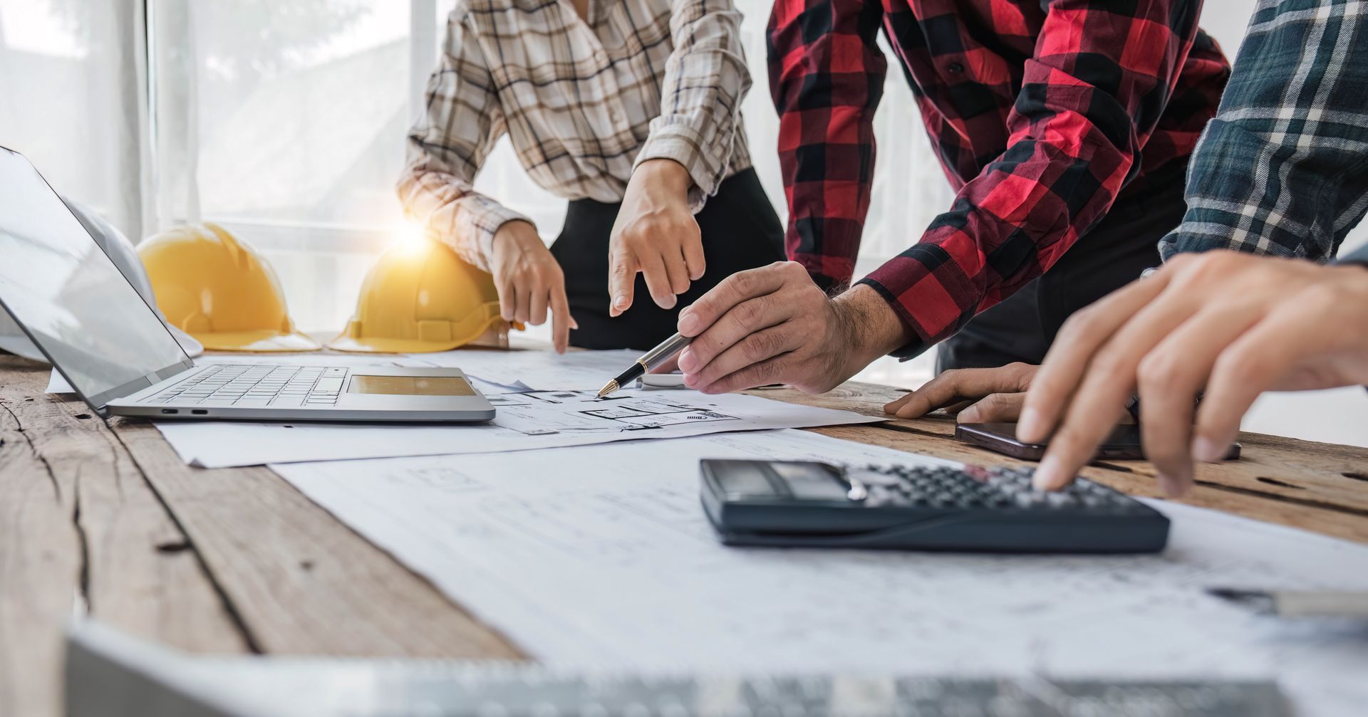 Un groupe d'ouvriers du bâtiment sont assis à une table et regardent un plan.