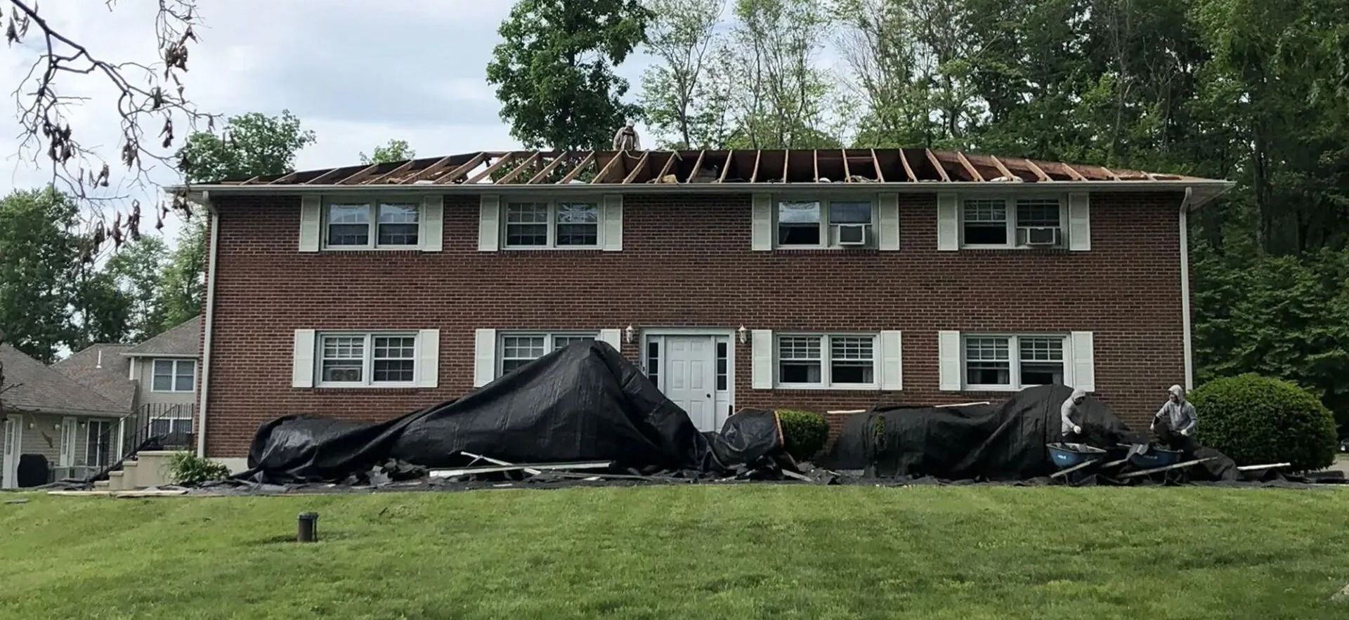 A large brick house with a roof that has been damaged by a storm.