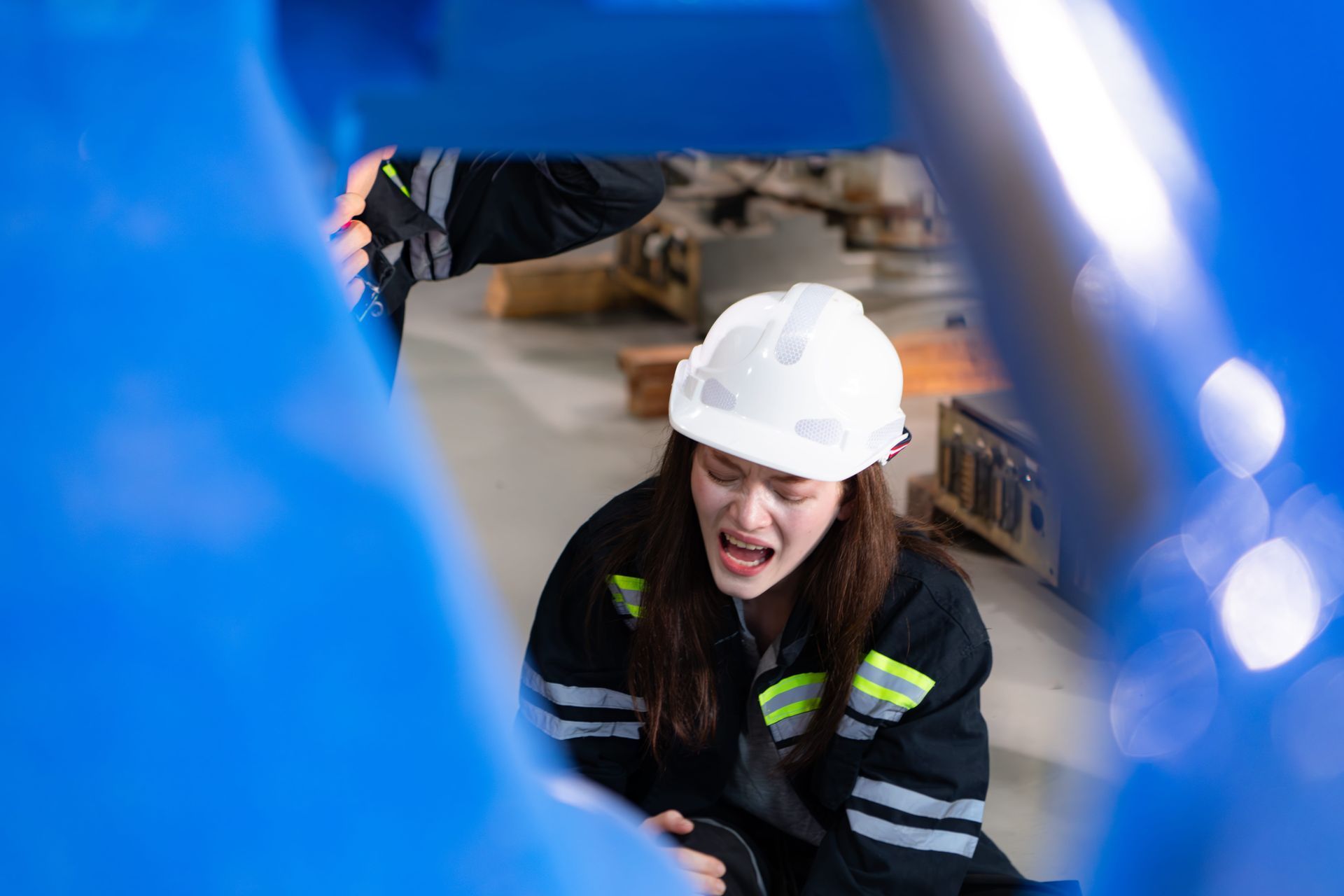 A woman wearing a hard hat and safety glasses is sitting on the ground.