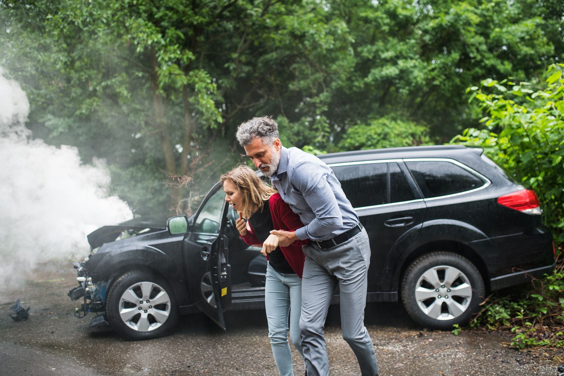 A man is helping a woman out of a car after accident