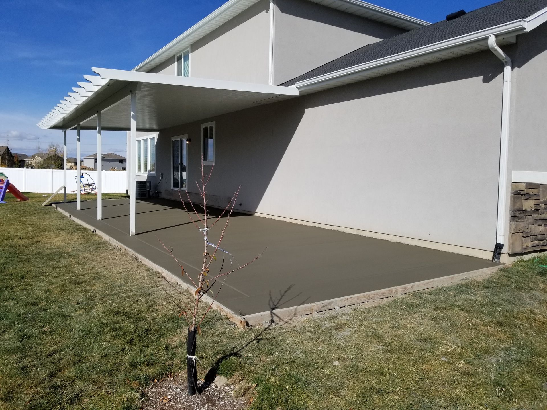 A brick driveway leading to a house with a lush green lawn.