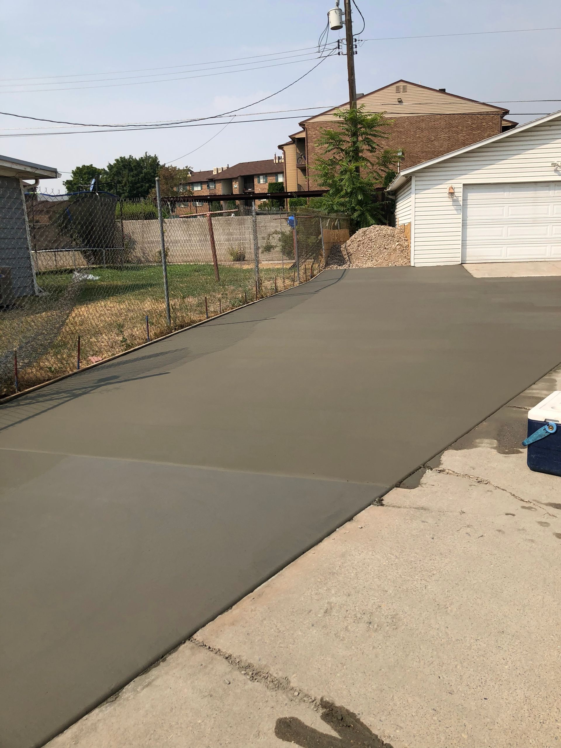 A concrete walkway leading to a house with a lush green lawn.