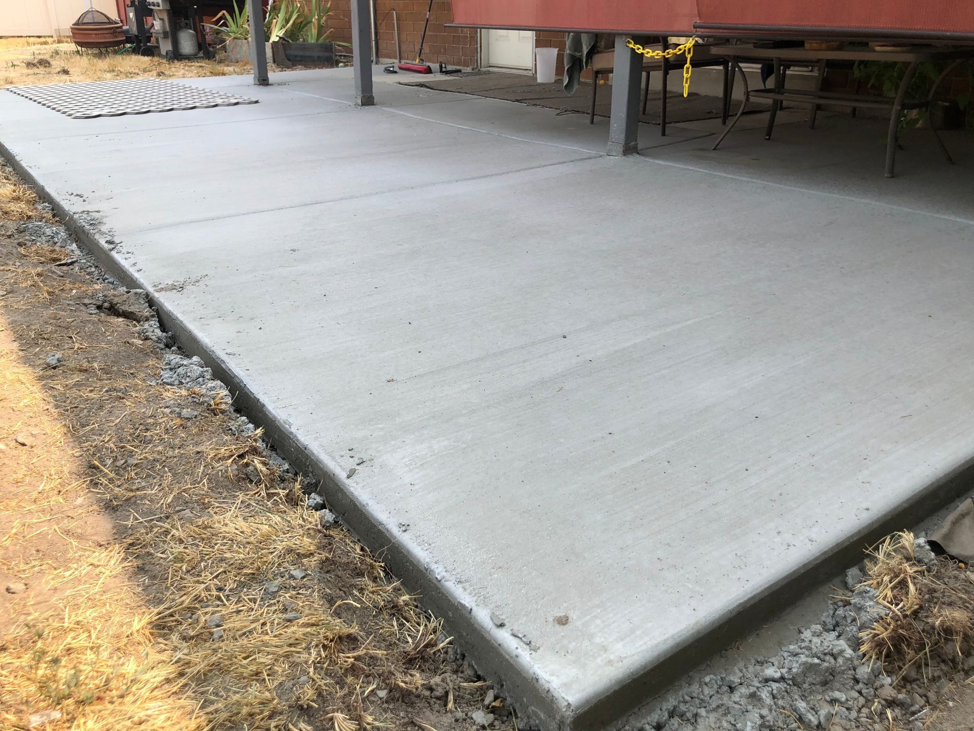 A concrete walkway leading to a house with a lush green lawn.