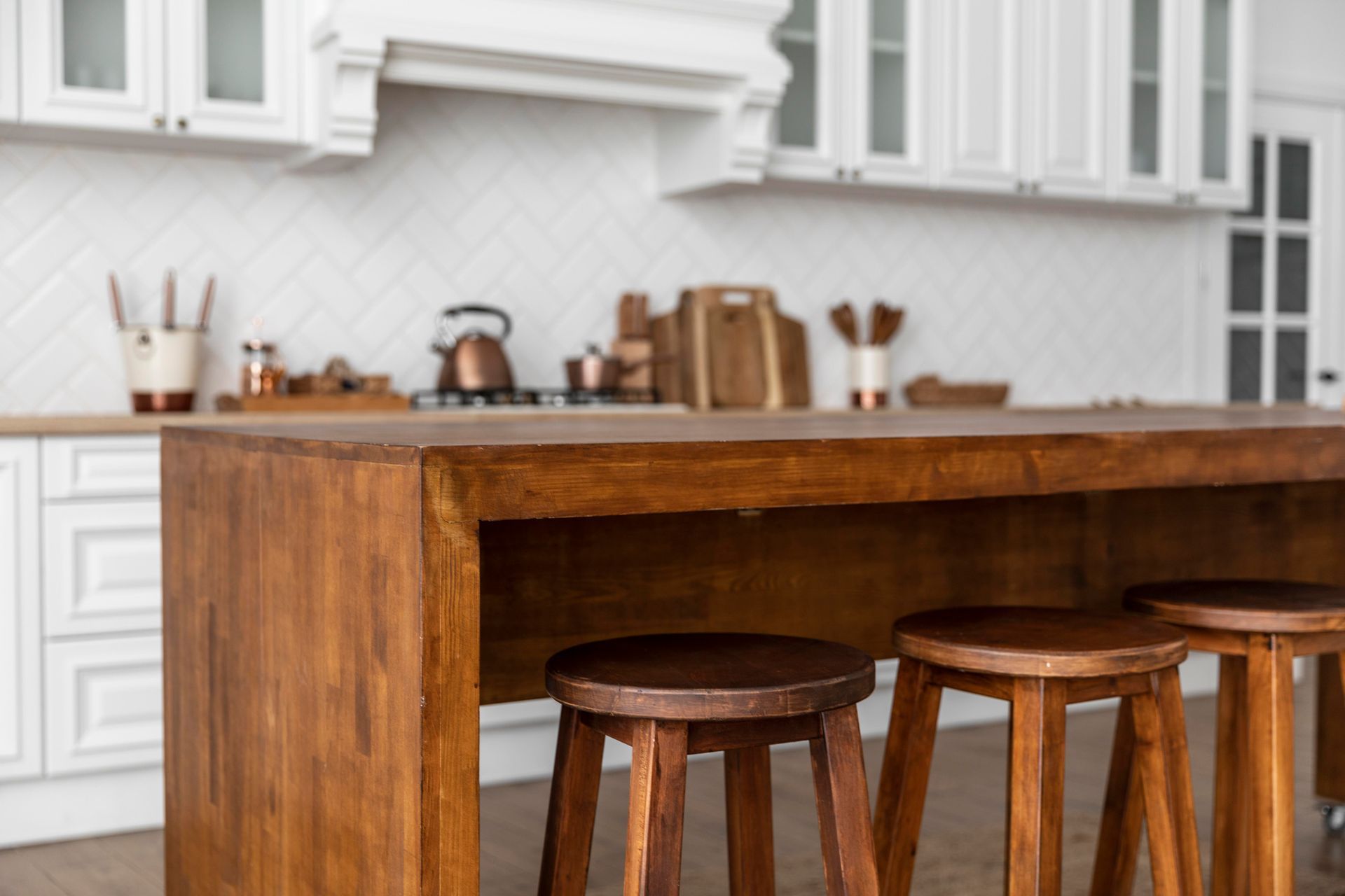 A kitchen with a wooden table and three wooden stools.