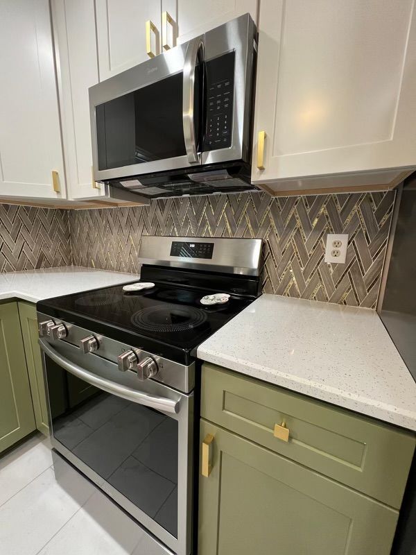 A kitchen with a stove , microwave , and cabinets.