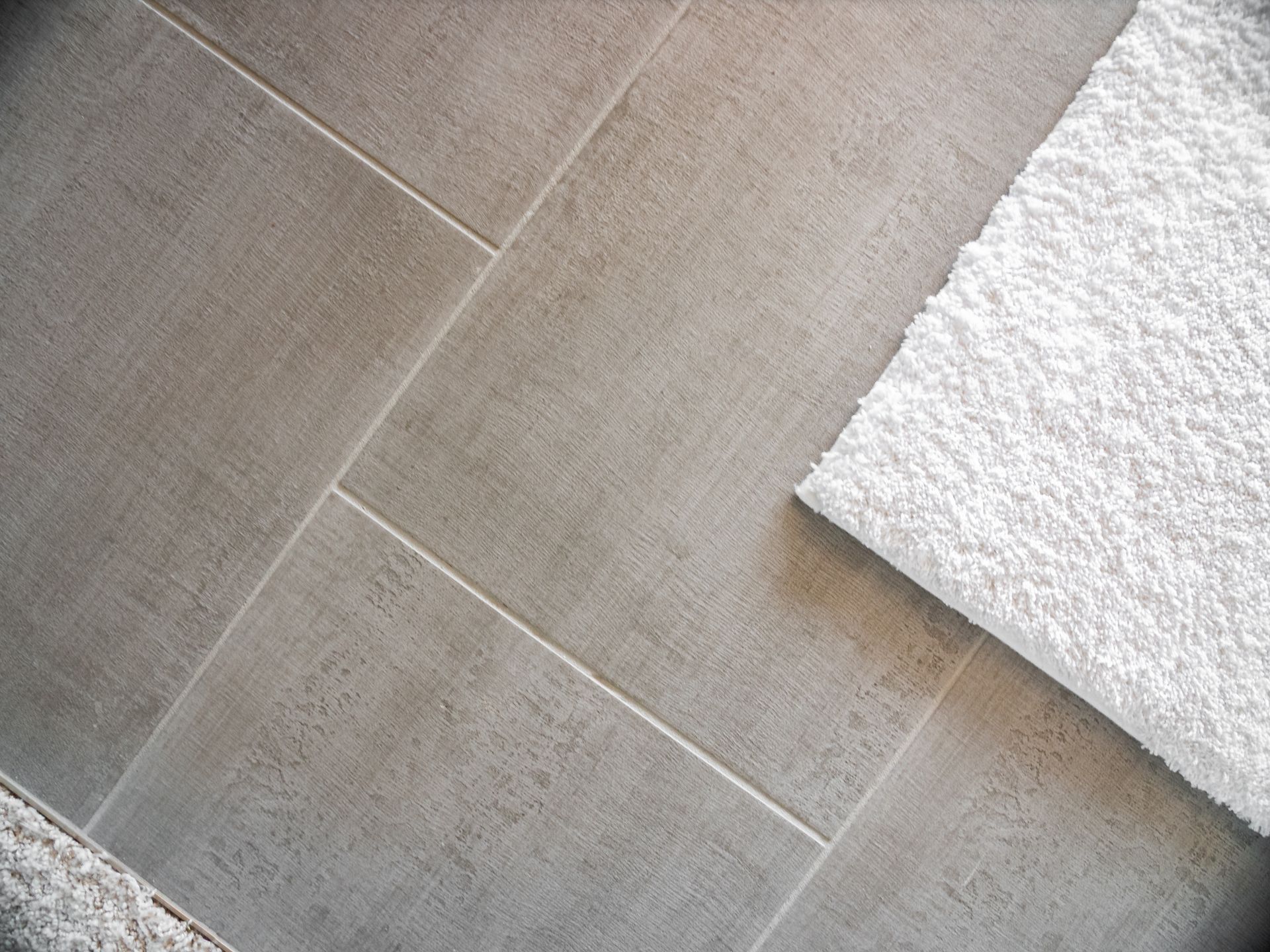 Gray tiled floor with a white fluffy towel.