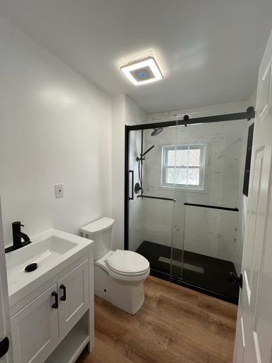 A bathroom with a toilet , sink , shower and window.