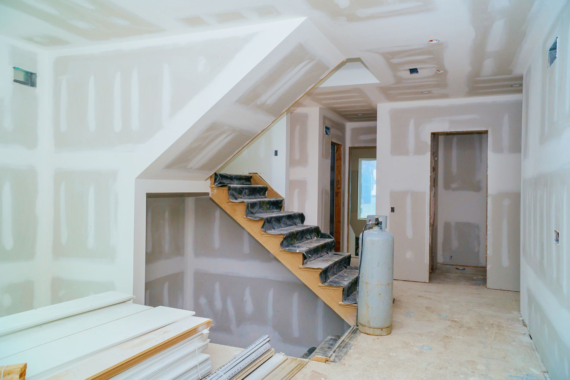 Interior under construction; drywall installed around staircase and doorway.