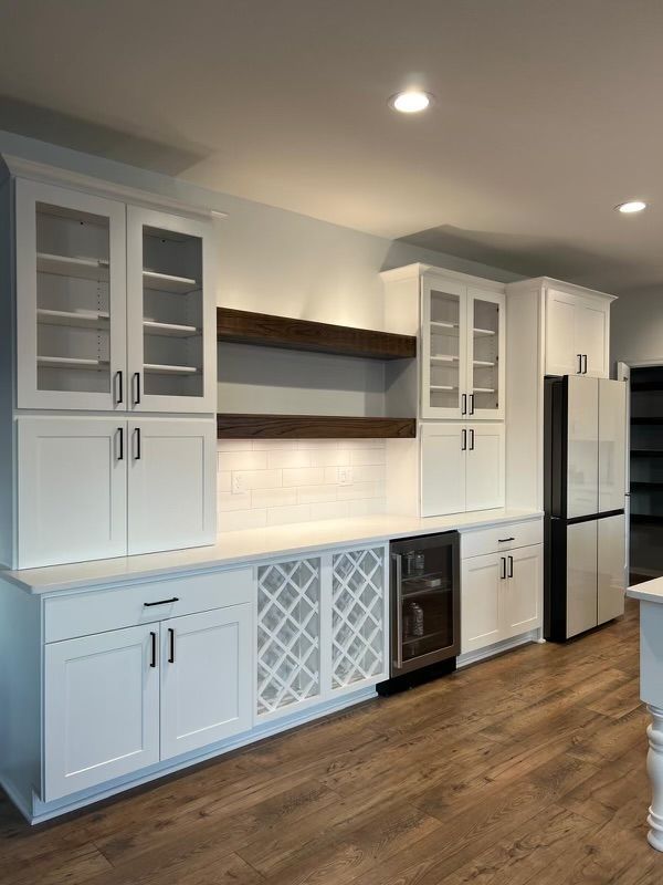 A kitchen with white cabinets , a refrigerator , and a wine cooler.