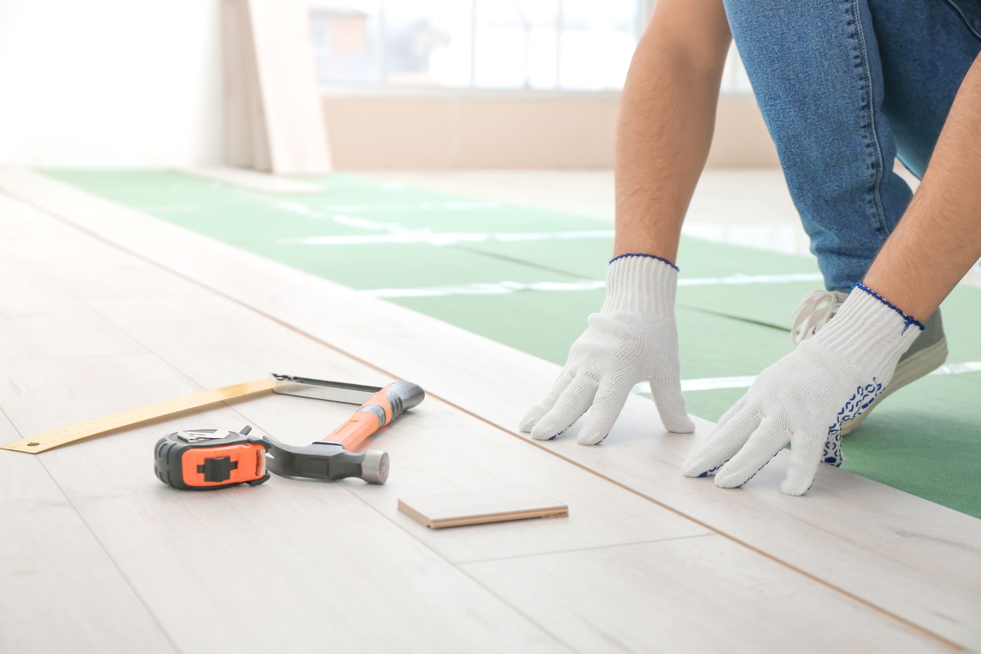 A person is installing a wooden floor in a room.