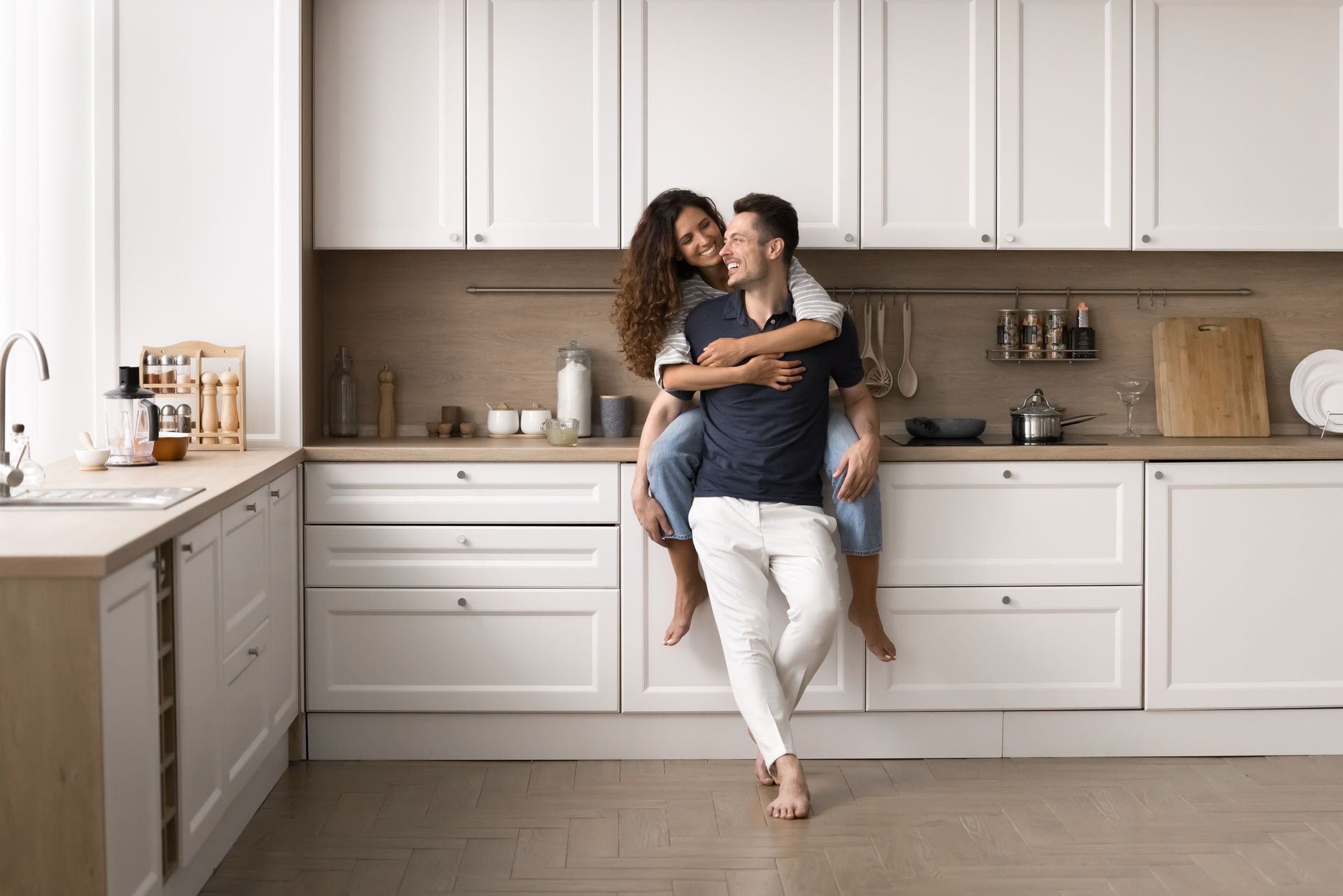 A man is carrying a woman on his back in a kitchen.